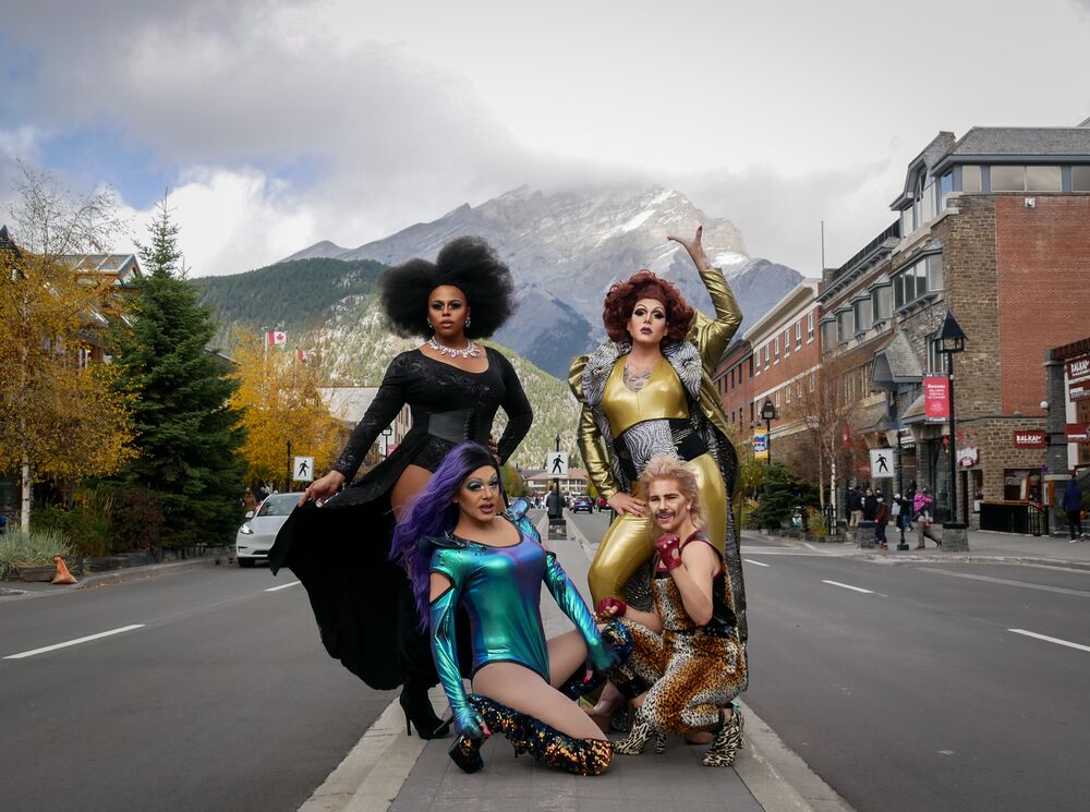 Four drag performers pose on Banff Ave with Cascade Mountain in the background